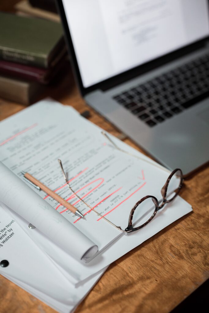 pexels photo 8036339 8036339 Glasses and documents on a desk with a laptop, representing a busy workspace.